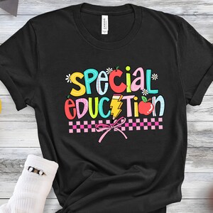 May include: Black t-shirt with the text "Special Education" in colorful letters with a pink bow and checkered pattern.