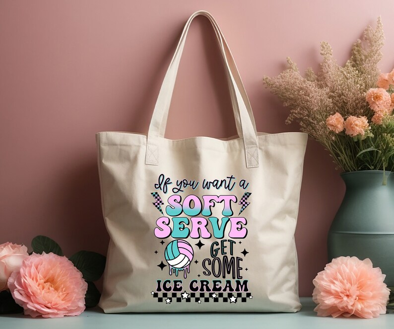 Pode incluir: Uma bolsa tote de lona branca com um gr&aacute;fico rosa, azul e verde que diz "Se voc&ecirc; quer um soft serve, pegue um sorvete". O gr&aacute;fico tamb&eacute;m inclui uma bola de voleibol com um design rosa e azul.