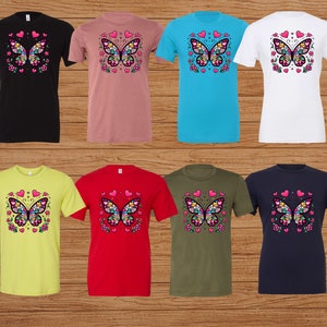 May include: Eight t-shirts with a colorful butterfly design on the front. The shirts are in different colors, including black, pink, blue, white, yellow, red, green, and navy.