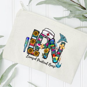 Peut inclure: Une pochette zipp&eacute;e en toile blanche avec un graphique color&eacute; des lettres "LPN" compos&eacute; de divers symboles m&eacute;dicaux et de tournesols. Le texte "Licensed Practical Nurse" est imprim&eacute; sous le graphique.
