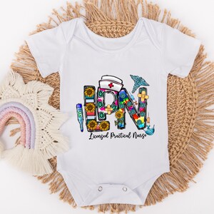 Peut inclure: Combinaison blanche pour b&eacute;b&eacute; avec un graphique color&eacute; des lettres LPN, compos&eacute; de symboles m&eacute;dicaux et de tournesols. Le texte "Licensed Practical Nurse" est sous le graphique.