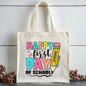May include: Cream-colored tote bag with the text "HAPPY FIRST DAY OF SCHOOL" in colorful bubble letters. A yellow pencil graphic with the text "#LETSDOTHIS" is on the right side of the bag. The bag has two cream-colored handles.