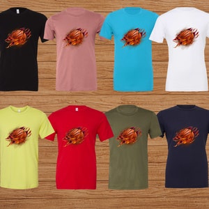 May include: A set of ten t-shirts featuring a basketball bursting through the fabric. The shirts are in various colors, including black, pink, blue, white, yellow, red, green, and navy.