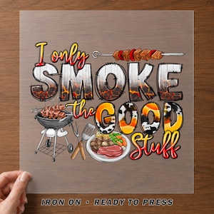 May include: A graphic transfer featuring the text I only SMOKE the GOOD Stuff. The design includes a skewer of meat, a charcoal grill, a spatula, and a plate with a steak and vegetables. The lettering has a fiery, cow print, and wood texture.