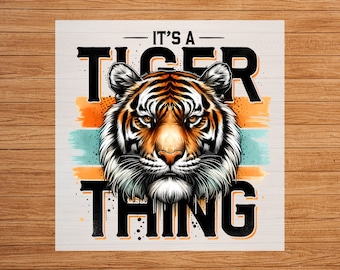 May include: A graphic design with a tiger face in the center. The tiger has orange and black stripes. The text "It's a Tiger Thing" is written in black letters above and below the tiger.