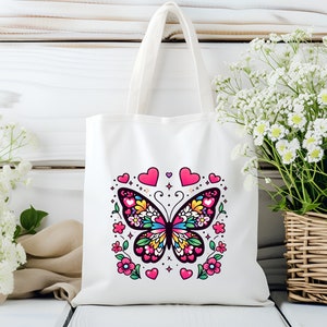 May include: White canvas tote bag with a colorful butterfly design and pink hearts. The butterfly has black wings with colorful details and is surrounded by pink hearts and flowers.