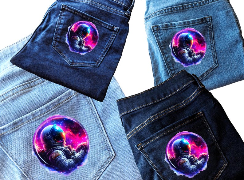 Pode incluir: Quatro pares de cal&ccedil;as de ganga com um patch de astronauta colorido no bolso de tr&aacute;s. O astronauta &eacute; retratado numa cena espacial com um capacete azul e um fundo de nebulosa rosa e roxa vibrante.