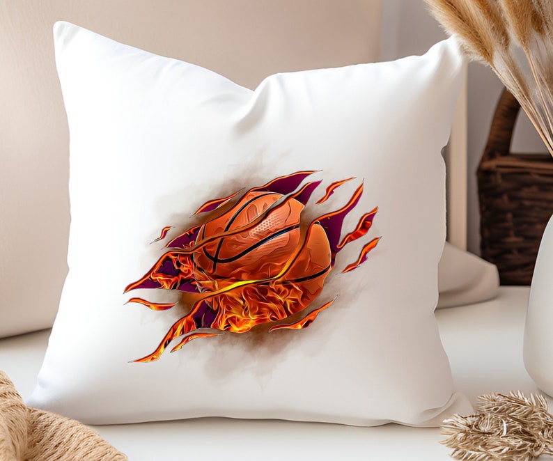 May include: White pillow with a basketball on fire bursting through the fabric. The basketball is orange and brown with flames in shades of orange and yellow.