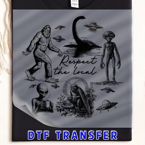 May include: Black t-shirt with a gray graphic featuring Bigfoot, the Loch Ness Monster, aliens, and UFOs. The phrase "Respect the local" is written in script. The words "DTF TRANSFER" are in a blue banner at the bottom.