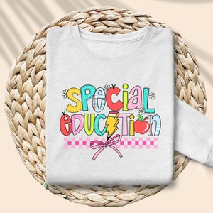 May include: White sweatshirt with the words "Special Education" in colorful letters with a pink bow and checkered pattern.