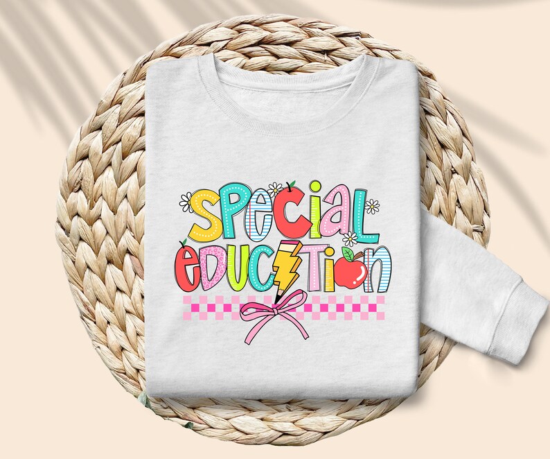 May include: White sweatshirt with the words "Special Education" in colorful letters with a pink bow and checkered pattern.