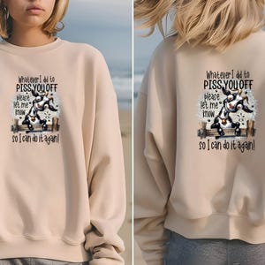 May include: Beige sweatshirt with a graphic of a goat on a fence and the text "Whatever I did to PISS YOU OFF, please let me know so I can do it again!" on the front and back. The sweatshirt is a neutral color.