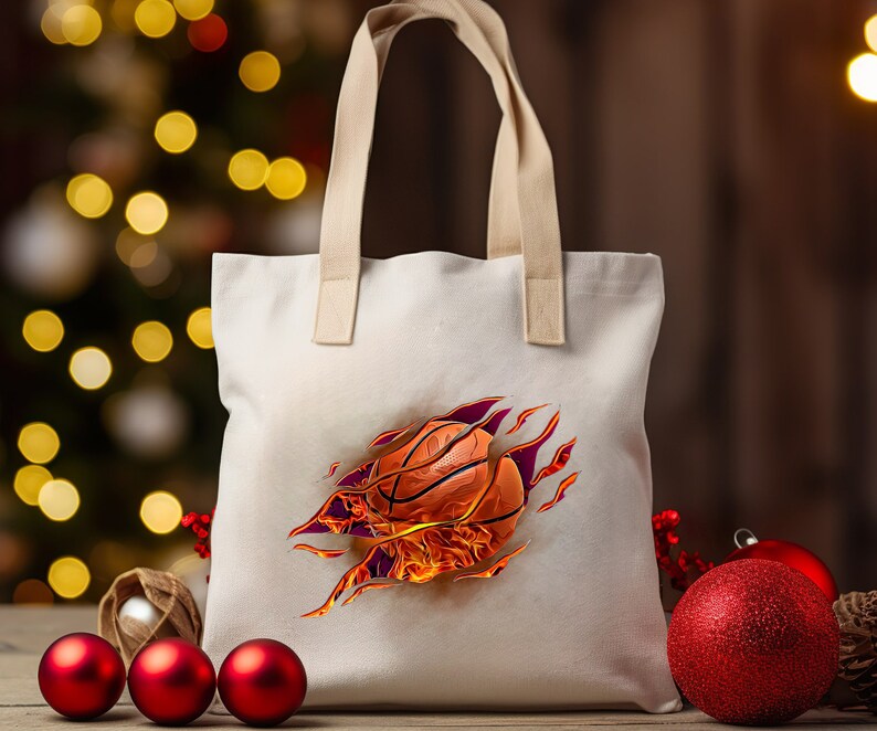 May include: A white canvas tote bag with a design of a basketball on fire. The basketball is orange and black with red flames.