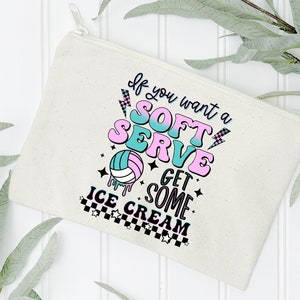 Pode incluir: Uma bolsa de lona branca com z&iacute;per com um gr&aacute;fico rosa e azul que diz "Se voc&ecirc; quiser um soft serve, pegue um pouco de sorvete". O gr&aacute;fico tamb&eacute;m inclui uma bola de v&ocirc;lei e estrelas.