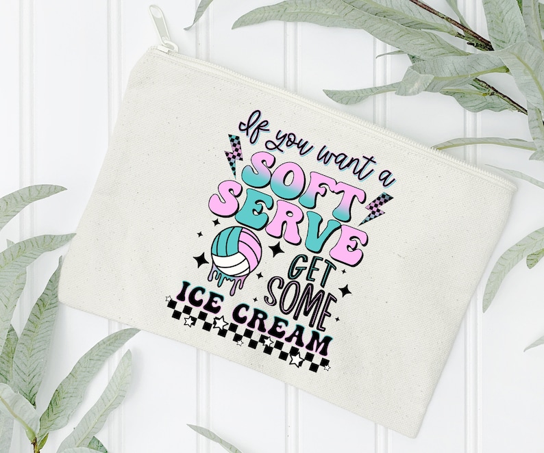 Pode incluir: Uma bolsa de lona branca com z&iacute;per com um gr&aacute;fico rosa e azul que diz "Se voc&ecirc; quiser um soft serve, pegue um pouco de sorvete". O gr&aacute;fico tamb&eacute;m inclui uma bola de v&ocirc;lei e estrelas.