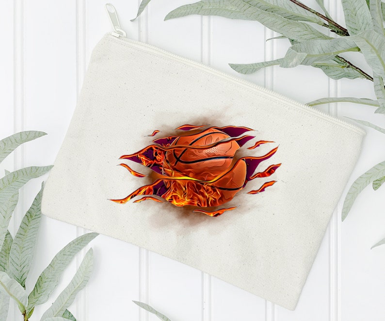 May include: A white canvas zippered pouch with a basketball on fire graphic. The basketball is orange and brown with black lines. The flames are orange and yellow.