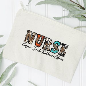 May include: A white canvas zippered pouch with the word "NURSE" in colorful patterned letters. The text "Coffee. Scrubs. Rubbers. Gloves" is printed below the word "NURSE".