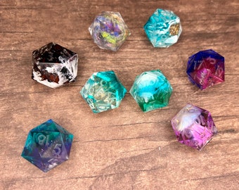 May include: Assortment of polyhedral dice in various colors, including blue, purple, green, and white. The dice are made of resin and feature embedded glitter and other decorative elements. Ideal for tabletop gaming.