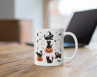 May include: White ceramic mug featuring Halloween-themed illustrations. The design includes black cats, jack-o'-lanterns, ghosts, bats, and a witch's hat. The mug is on a wooden surface with a laptop in the background.