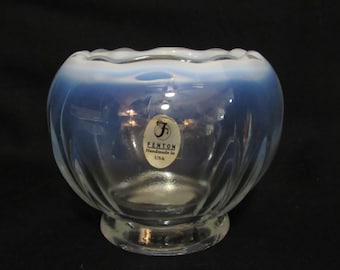 May include: A clear glass bowl with a ruffled rim and a blue-to-clear gradient. The bowl has a round base and a label that reads "Fenton Handmade in USA."