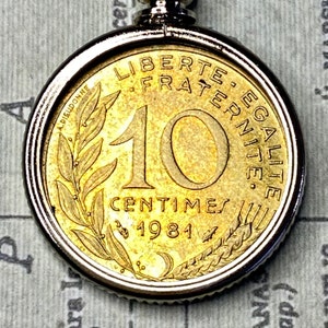 May include: A gold-coloured French 10 centimes coin from 1981. The coin features the words "Liberte, Egalite, Fraternite" around the edge and a wreath of leaves on the bottom.