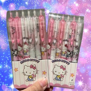 Può includere: Due confezioni da sei penne Hello Kitty. Le penne sono rosa e bianche con personaggi di Hello Kitty su di esse. Le confezioni sono rosa e bianche con il viso di Hello Kitty su di esse.