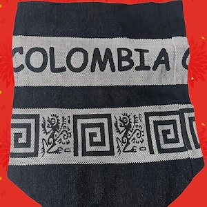 May include: A black textile item with the word "COLOMBIA" in white block letters. Below the text is a white band with a repeating geometric pattern and stylized figures. The background is red with floral designs.