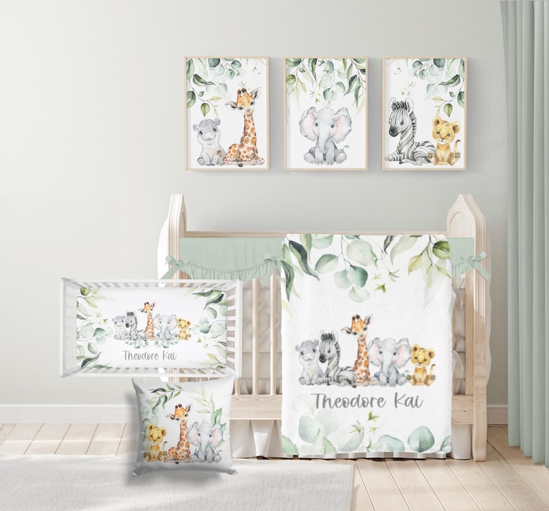 May include: A nursery set with watercolour animal illustrations. The set includes framed prints, a crib sheet, a pillow, and a blanket. The artwork features a giraffe, elephant, zebra, lion, and hippo. The colour scheme is soft with green foliage.