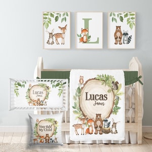May include: A woodland nursery set with a white blanket, pillow, and crib sheet featuring a woodsy theme with animals such as deer, foxes, bears, and owls. The blanket and crib sheet have the name "Lucas James" printed on them. The pillow has the text "Stay Wild My Child" printed on it.