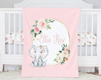 May include: Pink baby blanket with a watercolor illustration of an elephant wearing a floral crown. The blanket features the name "Ellia Rose" in cursive script within a gold oval frame, surrounded by floral accents.