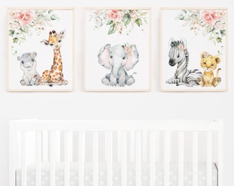 May include: Three framed watercolor prints featuring baby animals: a hippo and giraffe, an elephant, and a zebra with a lion cub. Each print has a floral border with pink roses and green leaves. The prints are displayed above a white crib.