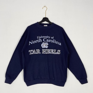 May include: Navy blue sweatshirt featuring the text "University of North Carolina" and "TAR HEELS" in white. The long-sleeved top has a crew neck.