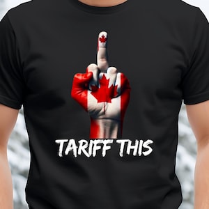 May include: A black t-shirt featuring a raised middle finger, painted in the colours of the Canadian flag, with the text "TARIFF THIS" in white.