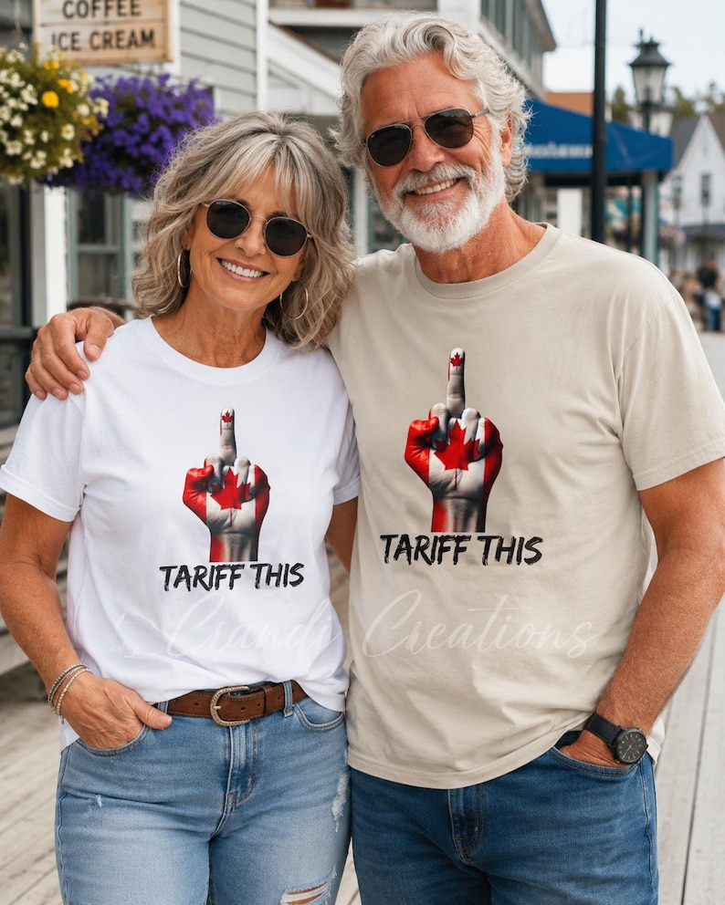 Puede incluir: Una camiseta blanca y una camiseta beige, cada una con un gr&aacute;fico de una mano pintada con la bandera canadiense haciendo un gesto de dedo medio. Debajo del gr&aacute;fico, el texto TARIFF THIS est&aacute; impreso en una fuente negra, negrita y desgastada.