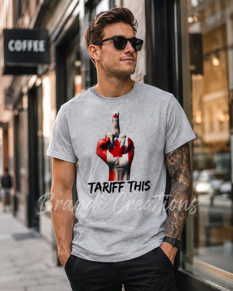 Puede incluir: Una camiseta gris jaspeado de manga corta con un gr&aacute;fico de una mano pintada con el dise&ntilde;o de la bandera canadiense, mostrando el dedo medio. Debajo del gr&aacute;fico, el texto TARIFF THIS est&aacute; impreso en una fuente negra, negrita y desgastada.