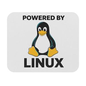 May include: White mousepad with rounded corners featuring the text "POWERED BY" above a cartoon penguin and the word "LINUX" below. The penguin is black, white, and yellow.