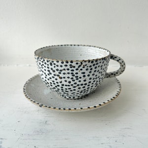 Danish handmade ceramic white coffee tea cup vessel and saucer with black spots. Drew Barrymore's choice of gift for the interior designer.