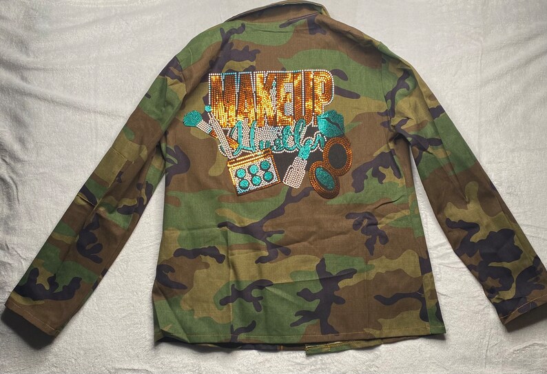 May include: Camouflage green jacket with a sparkly gold and turquoise design that says "Makeup Killer" on the back.
