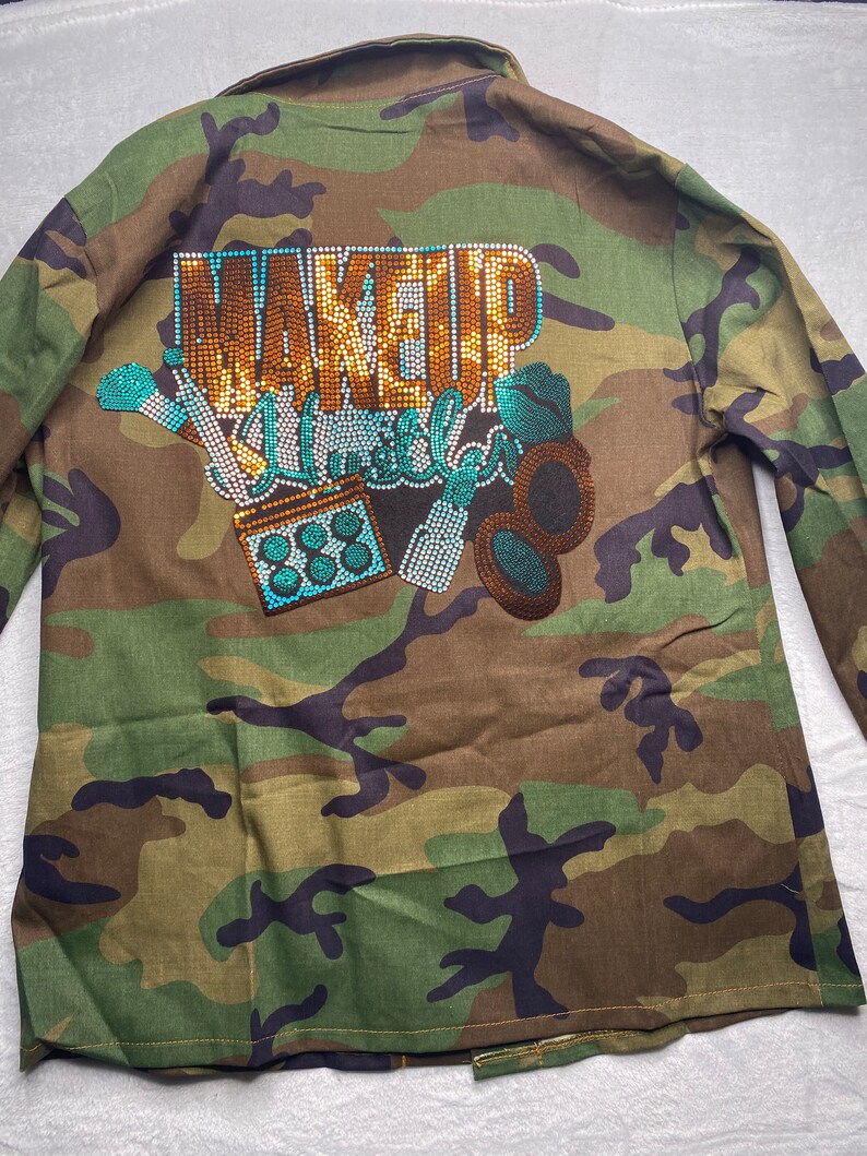 May include: Camouflage green utility jacket with a rhinestone design that says "Makeup Unleashed".