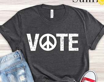 Op de afbeelding: Donkergrijs heather t-shirt met een wit peace-teken en het woord VOTE in een verweerd lettertype.