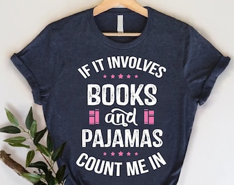 May include: A navy blue t-shirt with white text that reads "If it involves books and pajamas count me in". The text is in a distressed font and the words "books" and "pajamas" are highlighted in pink.