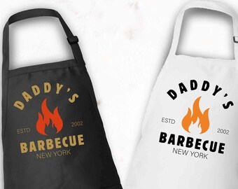 May include: Two black and white aprons with the text "Daddy's Barbecue Est. 2002 New York" and a flame graphic.