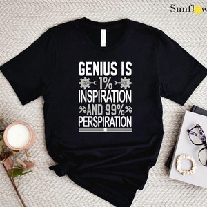 May include: Black t-shirt with white text that reads "Genius is 1% Inspiration and 99% Perspiration". The text is surrounded by small gear icons.