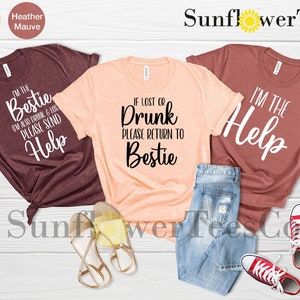 May include: Three t-shirts with different sayings. The first shirt is maroon and says "I'm the bestie, I'm also drunk & lost, please send help". The second shirt is peach and says "If lost or drunk, please return to bestie". The third shirt is maroon and says "I'm the help".