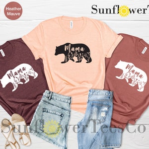 May include: Three t-shirts with a bear silhouette design and the word "Mama" inside the bear. The shirts are in maroon, peach, and mauve.