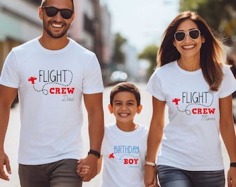 May include: A family of three wearing white t-shirts with red and black text that says "Flight Crew" with a small airplane graphic. The dad's shirt says "Dad", the mom's shirt says "Mom", and the child's shirt says "Birthday Boy".