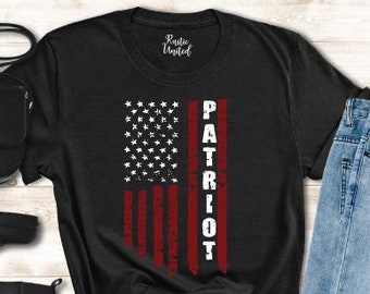 May include: Black t-shirt with a distressed American flag design and the word "PATRIOT" in white lettering.