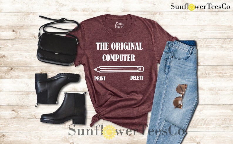 K&ouml;nnte beinhalten: Ein maroonfarbenes T-Shirt mit dem Text "THE ORIGINAL COMPUTER" und einer Bleistiftgrafik mit den W&ouml;rtern "PRINT" und "DELETE" darunter.