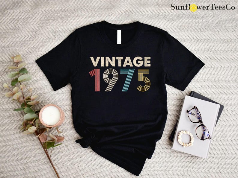 May include: Black t-shirt with the text "Vintage 1975" in rainbow colors. The numbers are in a retro font style.