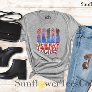 May include: A gray t-shirt with a graphic of raised fists in front of a stylized map of the United States. The graphic includes the text "Hispanic Heritage Month".